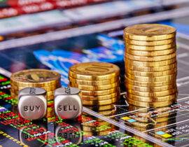 Uptrend stacks golden coins, dices cubes with the worsd SELL BUY on the financial stock charts as background. Selective focus